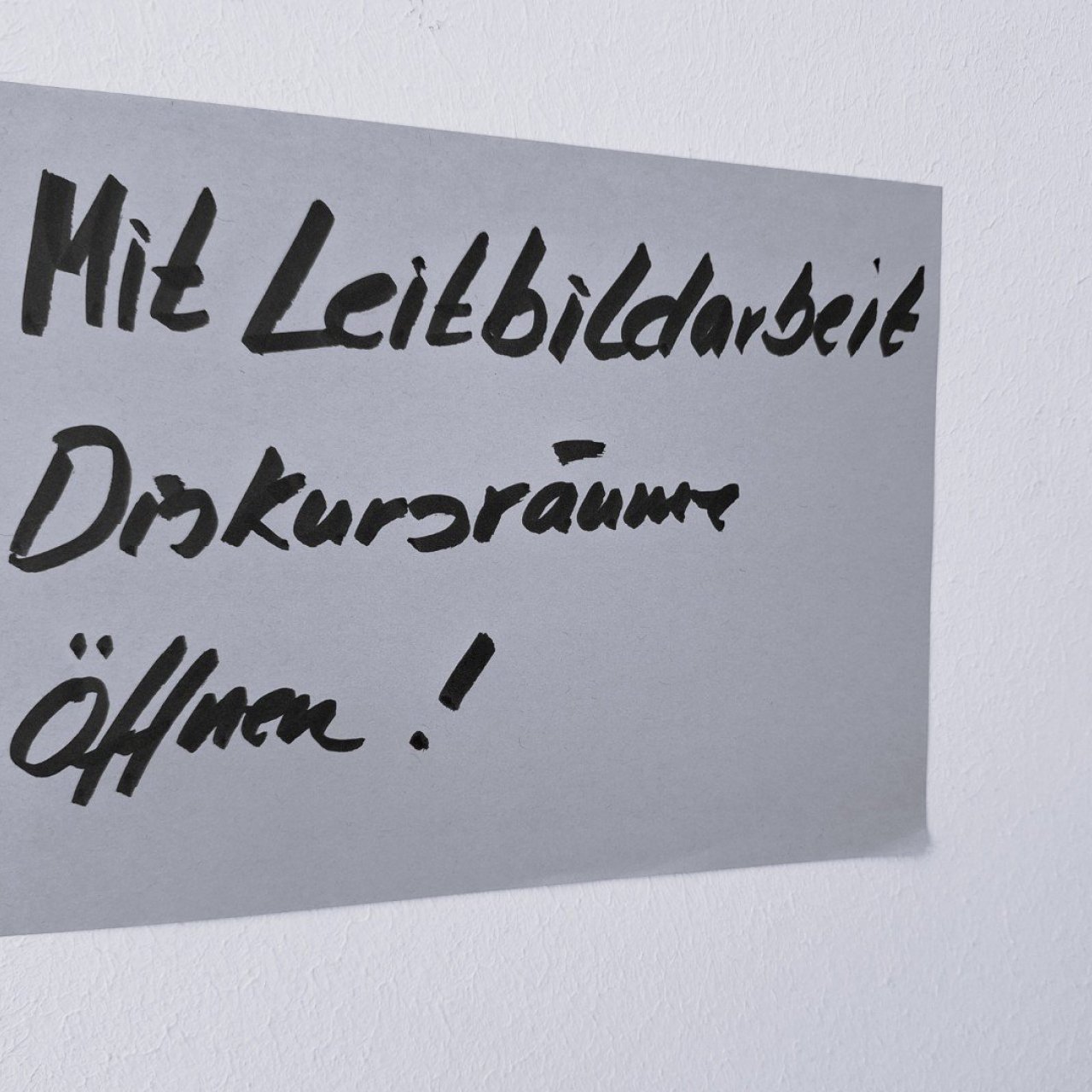 Das Bild zeigt ein PostIT auf dem steht, mit Leitbildarbeit Diskursr&auml;ume &ouml;ffnen. Das Bild entstand zum Auftakt unseres Beratungsprojektes.