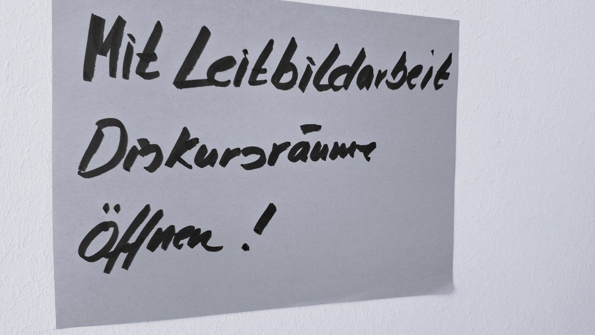 Das Bild zeigt ein PostIT auf dem steht, mit Leitbildarbeit Diskursr&auml;ume &ouml;ffnen. Das Bild entstand zum Auftakt unseres Beratungsprojektes.